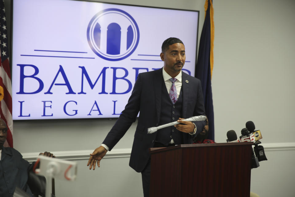 Attorney Justin Bamberg holds up a stick that he said a 911 called mistook for a gun that led to an officer stomping his client in the neck during Bamberg's news conference on Tuesday, Aug. 3, 2021 in Orangeburg, South Carolina. Orangeburg Public Safety officer David Lance Dukes was fired and charged with a felony after the July 26 incident. (AP Photo/Jeffrey Collins)