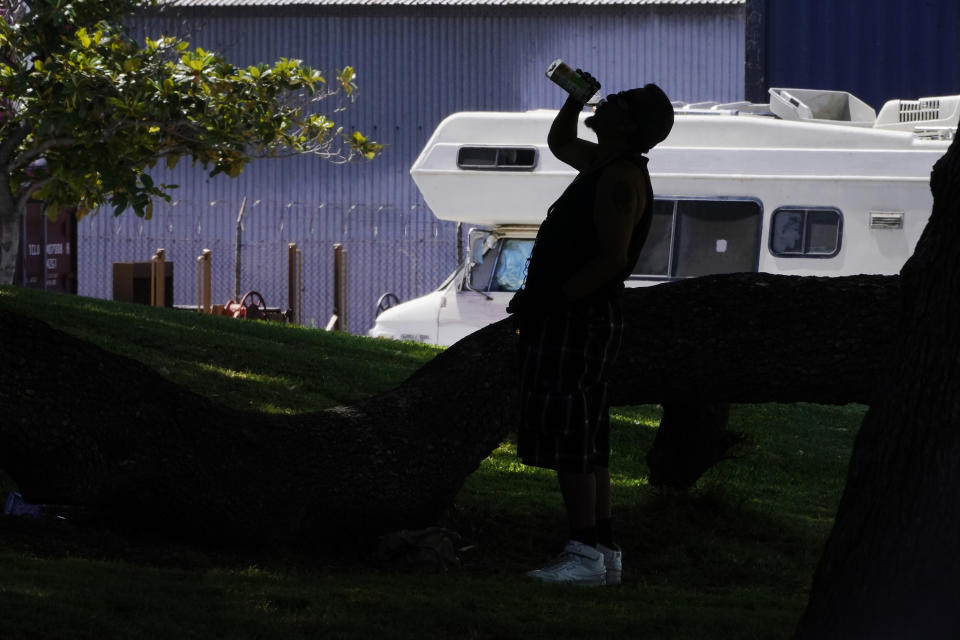 A man drinks water under a tree in shade during excessive heat at Lincoln Park in Los Angeles, Thursday, July 13, 2023. After a historically wet winter and a cloudy spring, California's summer was in full swing Thursday as a heat wave that's been scorching much of the U.S. Southwest brings triple digit temperatures and an increased risk of wildfires. (AP Photo/Damian Dovarganes)