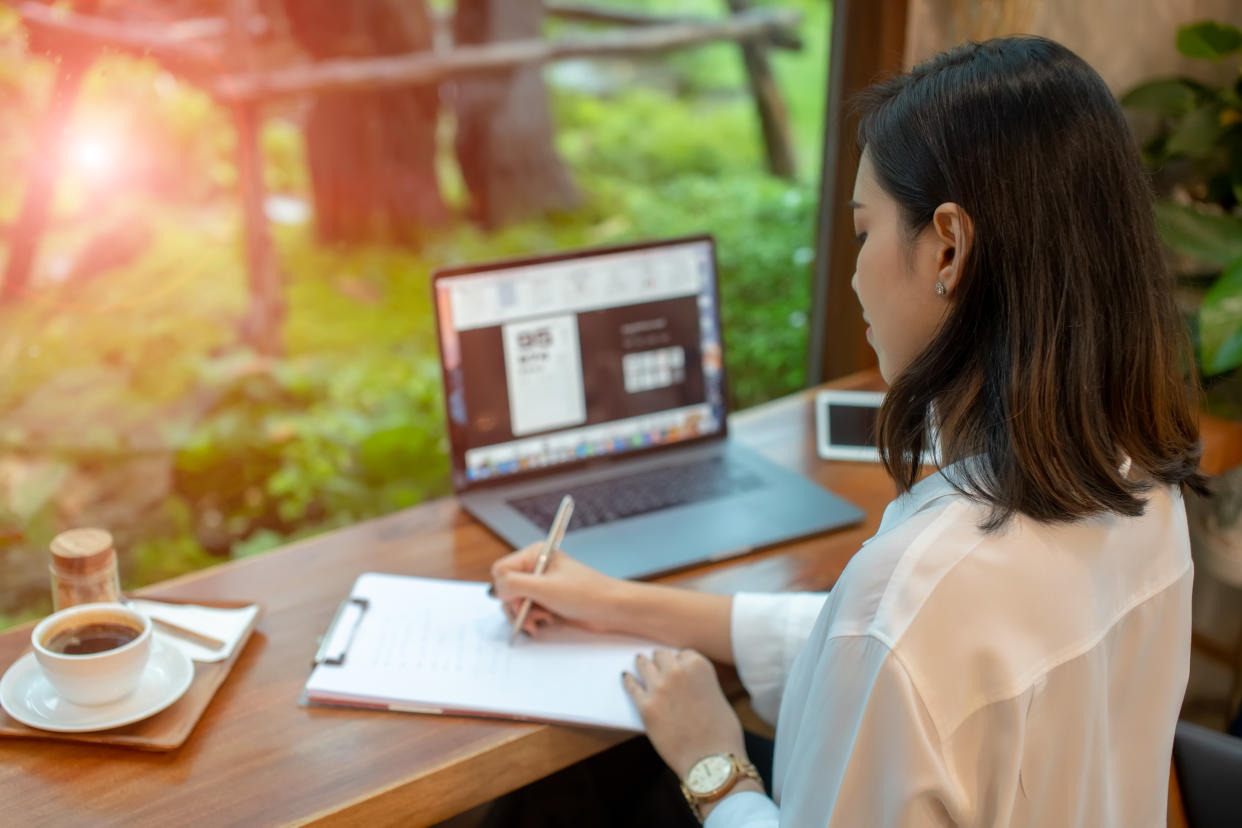 Asian woman are sitting thinking and writing with pen and open notebook in cafe. 