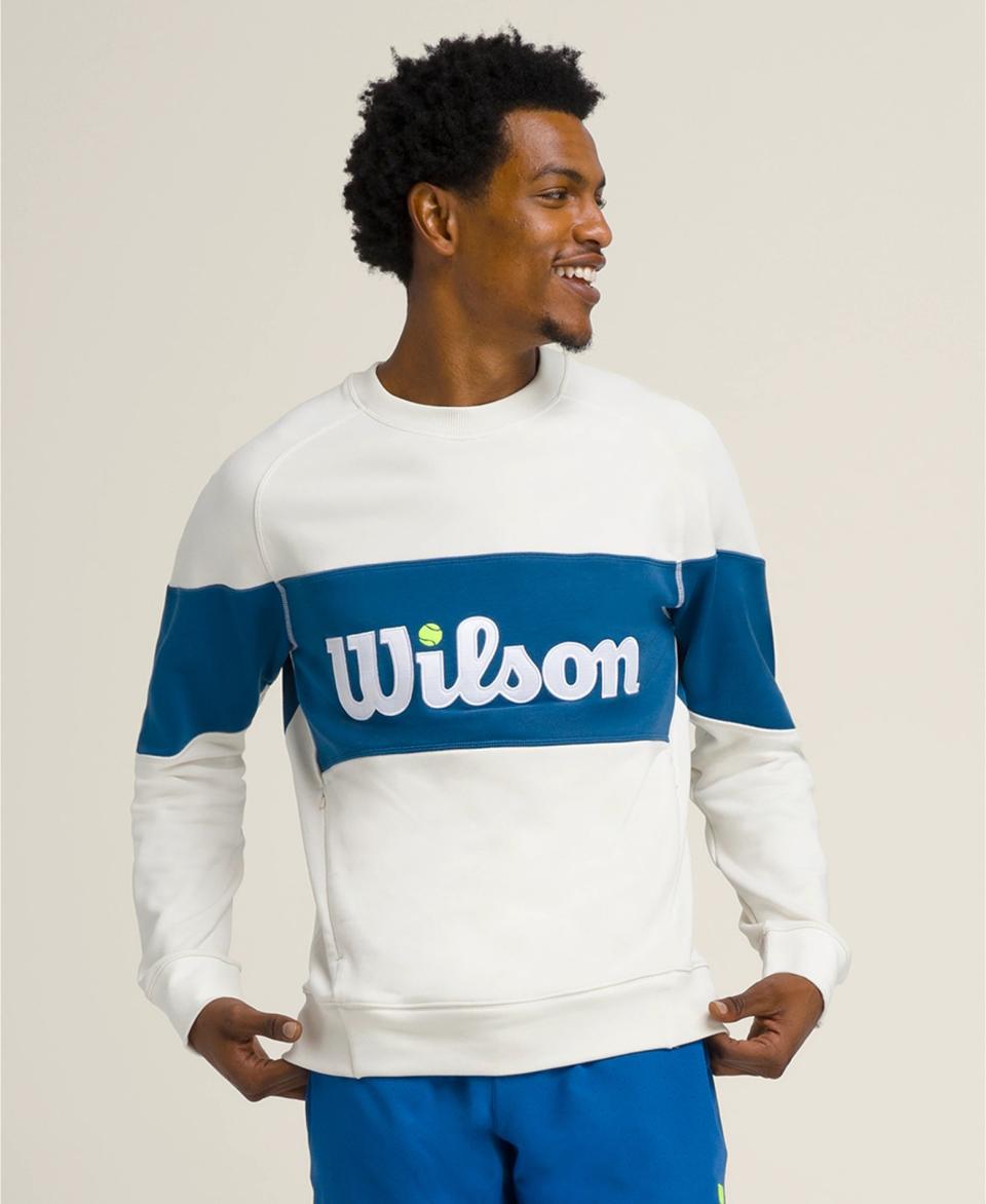 model wearing white and blue crewneck that reads "Wilson"