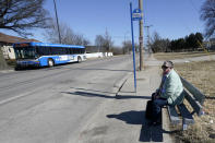 Pat Brown waits at a bus stop in Kansas City, Mo., Wednesday, March 3, 2021. Brown knows she needs the vaccine because her asthma and diabetes put her at higher risk of serious COVID-19 complications. But Brown hasn’t attempted to schedule an appointment and didn’t even know if they were being offered in her area yet; she says she is too overwhelmed. (AP Photo/Orlin Wagner)