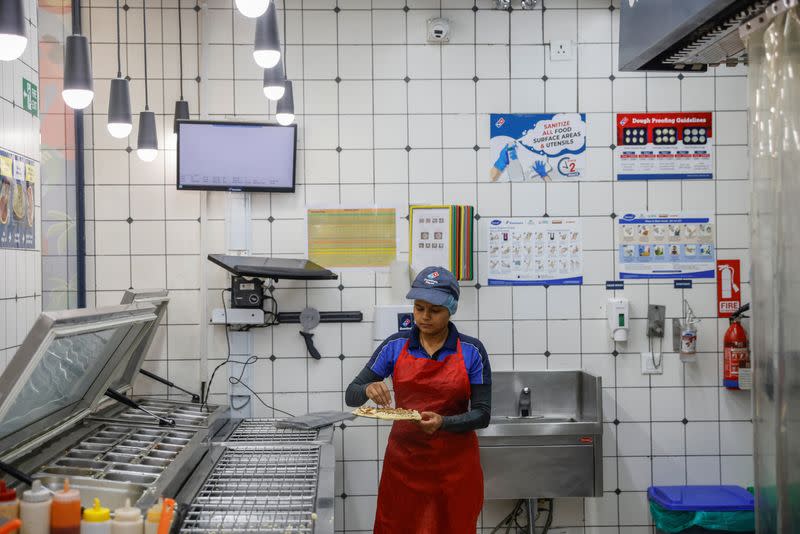 A staff member prepares a pizza at a Domino's restaurant in Noida