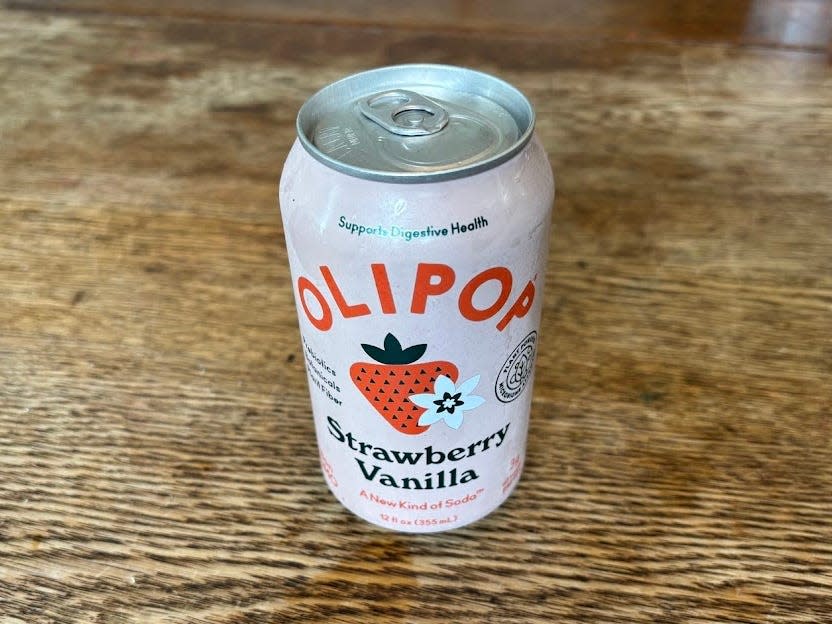 A can of strawberry-vanilla Olipop on a wooden table.