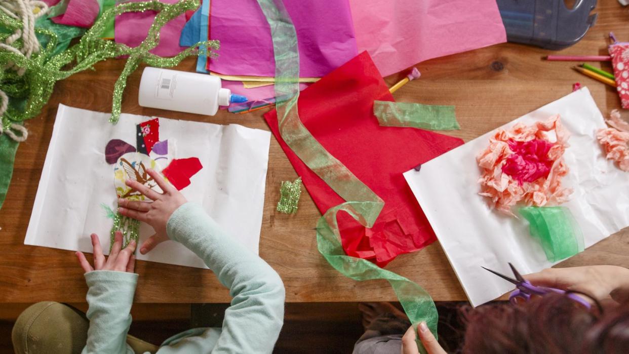 topdown view of two children doing arts and crafts at a wooden table