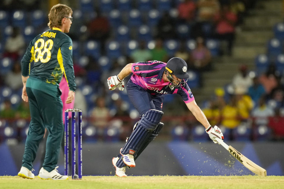 Scotland's captain Richie Berrington, right, reaches out to make his ground as Australia's Adam Zampa watches during the men's T20 World Cup cricket match between Australia and Scotland, at Darren Sammy National Cricket Stadium, Gros Islet, St Lucia, Saturday, June 15, 2024. (AP Photo/Ramon Espinosa)