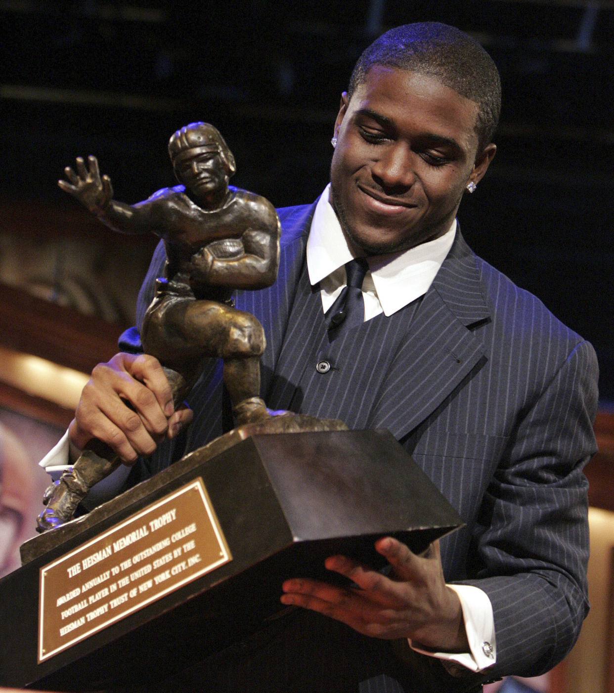 FILE - Southern California tailback Reggie Bush picks up the Heisman Trophy after being announced as the winner of the award Saturday, Dec. 10, 2005, in New York. Reggie Bush, whose Heisman Trophy victory for Southern California in 2005 was vacated because of NCAA violations, was among 18 players in the latest College Football Hall of Fame class announced Monday. (AP Photo/Julie Jacobson, File)