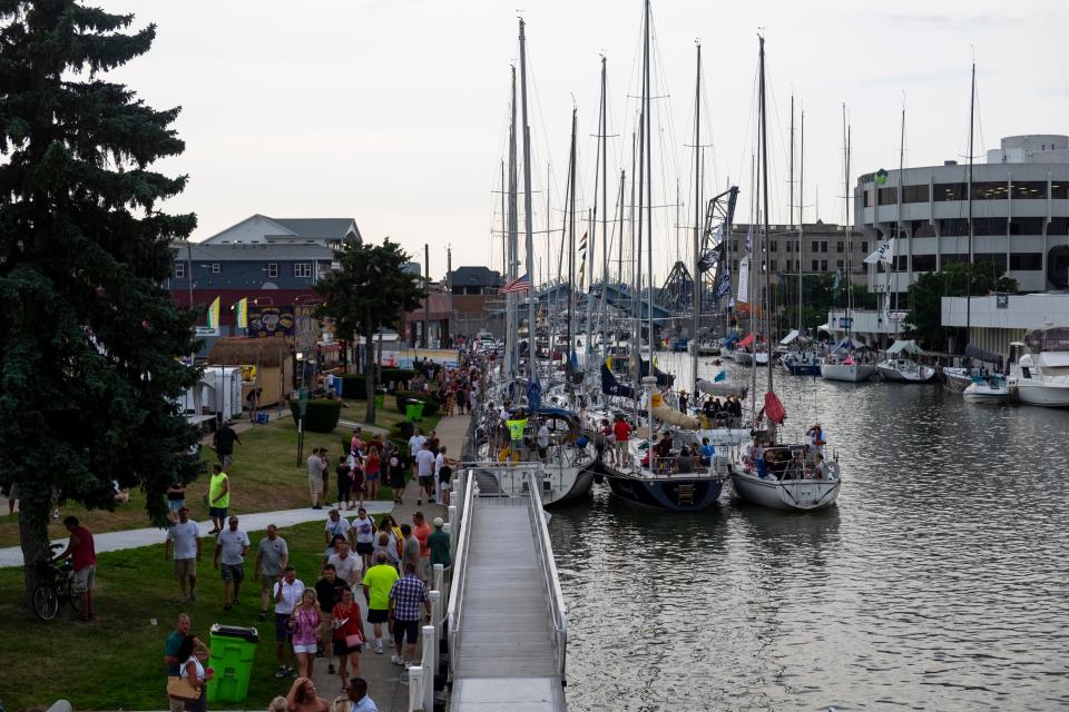 People walk along the Black River in Port Huron Friday, July 19, 2019, on Boat Night.