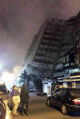 <p>In this photo released by Hualien County Fire Bureau, Taiwanese people watching a building that collapsed on its side from an early morning earthquake in Hualien County, eastern Taiwan, early Feb. 7 2018. (Photo: Hualien County Fire Bureau via AP) </p>