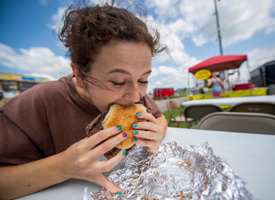 Herald-Times reporter Maya Gray eats a ribeye sandwich from JD's Ribeye at the Monroe County Fair at the Monroe County Fairgrounds on Monday, July 3, 2023.