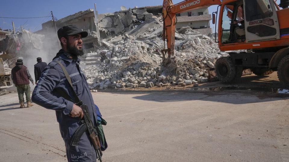 FILE - An al-Qaida-linked Hayat Tahrir al Sham militant stands in front of a destroyed house in Atareb, Syria, Sunday, Feb. 12, 2023. (Hussein Malla/AP, File)