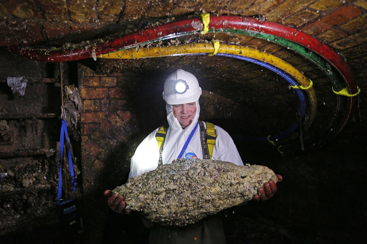 Tim Henderson, a "flusher" or trunk sewer technician holds a "fatberg" as he works in the intersection of the Regent Street and Victoria sewer in London on December 11, 2014.&nbsp; (Photo: ADRIAN DENNIS via Getty Images)