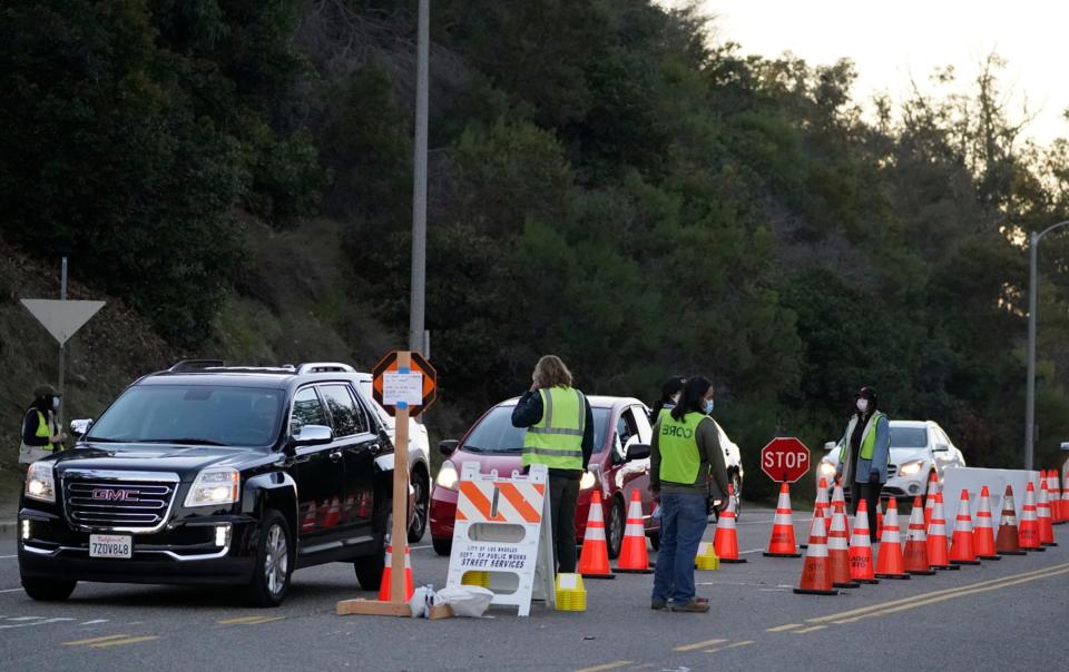 Drivers with a vaccine appointment enter a mega COVID-19 vaccination site set up in the parking lot of Dodger Stadium in Los Angeles Saturday, Jan. 30, 2021. One of the largest vaccination sites in the country was temporarily shut down Saturday because dozen of protesters blocked the entrance.