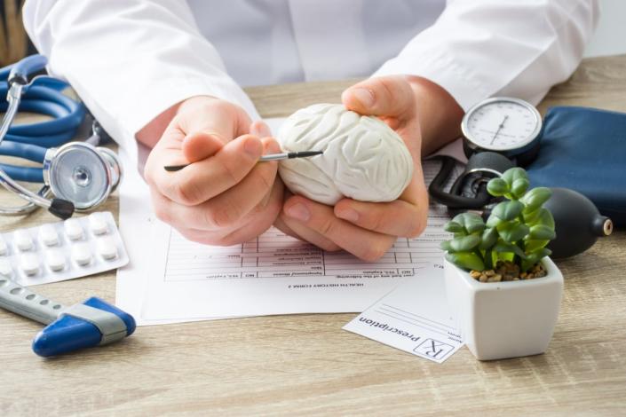 At doctors appointment physician shows to patient shape of brain with focus on hand with organ. Scene explaining patient causes and localization of diseases of brain, nerves and nervous system