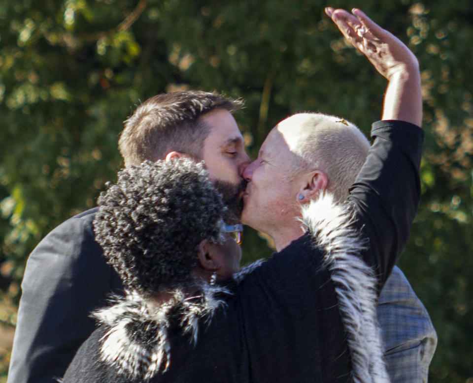 Danny Leclair, rear left, kisses his partner Aubrey Loots, right, as the couple from Los Angeles were married by Rev. Alfreda Lanoix, center, of the Unity Fellowship Church of Christ aboard the AIDS Healthcare Foundation's float "Living the Dream" during the 125th Tournament of Roses Parade in Pasadena, Calif., Wednesday, Jan. 1, 2014. (AP Photo/Ringo H.W. Chiu)