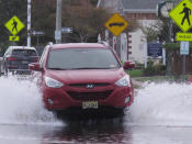 This Oct. 11, 2019, photo shows a car kicking up spray while driving through a flooded street in Bay Head, N.J. Bay Head is studying options to prevent, or at least reduce, incidents of so-called “sunny day” flooding caused by tides and rising sea levels, as well as major storm-related floods. New Jersey's Department of Environmental Protection and the U.S. Army Corps of Engineers have proposed a massive $16 billion plan to address back bay flooding along the shore. (AP Photo/Wayne Parry)