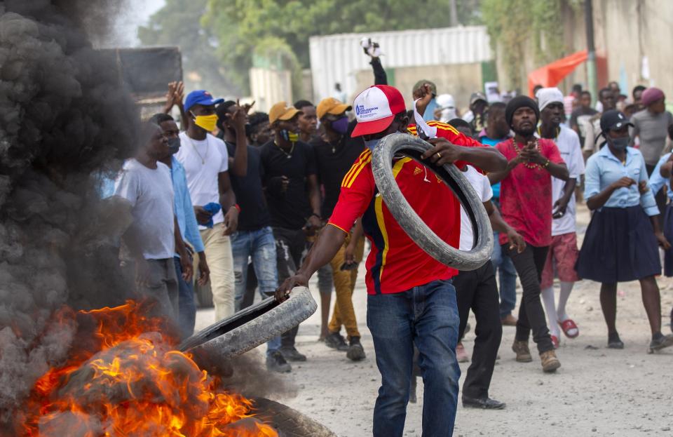 A protester adds tires to a burning barricade during a protest march to demand answers after the kidnapping and murder of high school senior Evelyne Sincère, in Port-au-Prince, Haiti, Thursday, Nov. 5, 2020. The young woman was found in a trash heap Sunday after relatives said they were unable to pay the large ransom demanded by her captors. Human rights groups contend the incident highlights the nation’s worsening security crisis. (AP Photo/Dieu Nalio Chery)