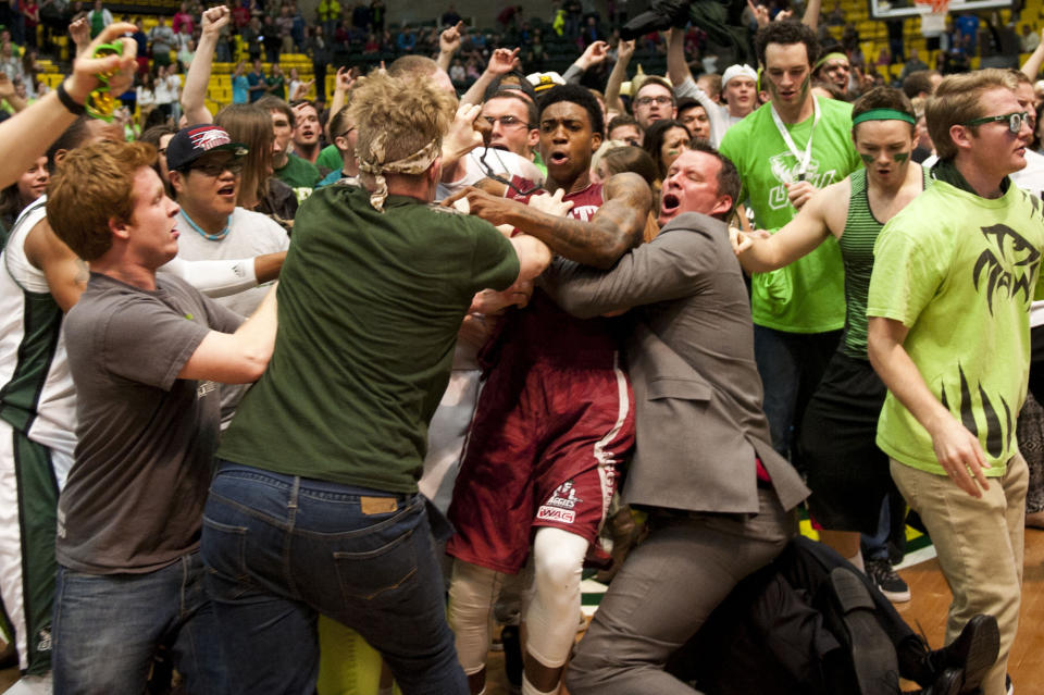 In this Thursday, Feb. 27, 2014 photo, New Mexico State's Daniel Mullings, at center in red and white jersey, is involved in a brawl involving players and fans who came onto the court when New Mexico State guard K.C. Ross-Miller hurled the ball at Utah Valley's Holton Hunsaker seconds after the Wolverines' 66-61 overtime victory against the Aggies in Orem, Utah. (AP Photo/The Daily Herald, Grant Hindsley) MANDATORY CREDIT