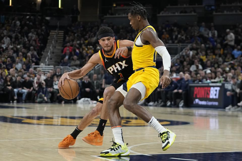Phoenix Suns' Devin Booker (1) is defended by Indiana Pacers' Bennedict Mathurin (00) during the first half of an NBA basketball game Friday, Jan. 26, 2024, in Indianapolis. (AP Photo/Darron Cummings)