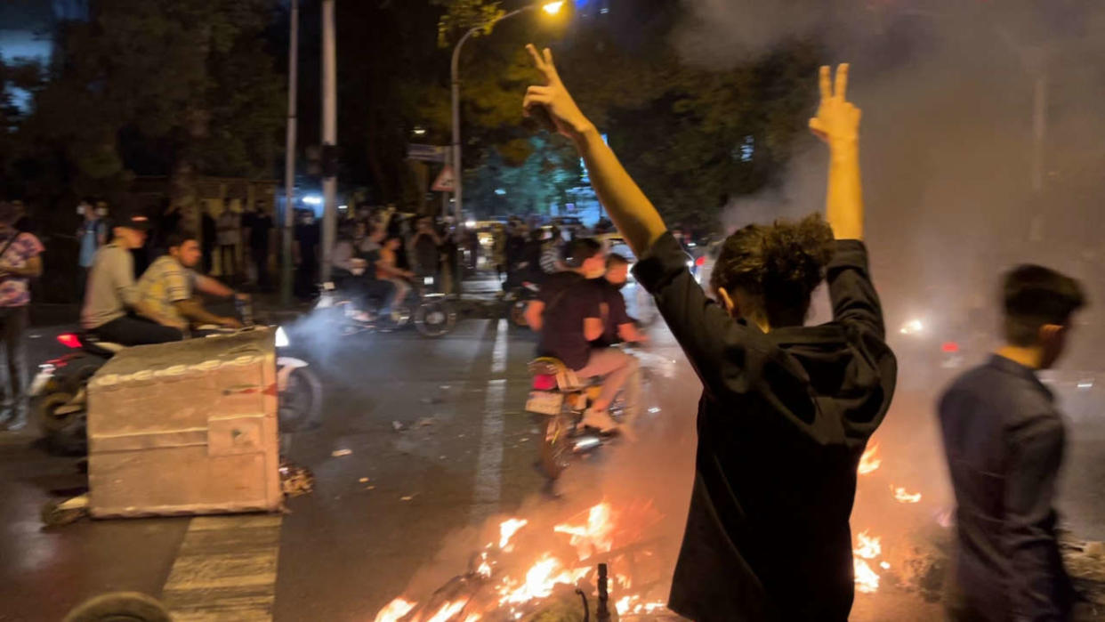 A demonstrator raises his arms and makes the victory sign during a protest for Mahsa Amini, a woman who died after being arrested by the Islamic republic's 