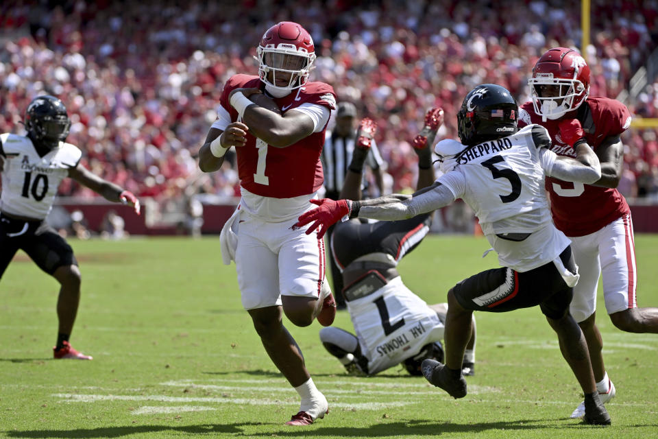 Arkansas quarterback KJ Jefferson (1) runs past Cincinnati defensive back Ja'Quan Sheppard (5) as teammate Matt Landers (right) blocks during a touchdown run on Saturday, Sept. 3, 2022, in Fayetteville, Ark. (AP Photo/Michael Woods)