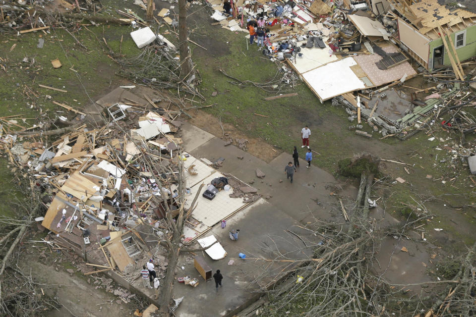 People walk between two destroyed houses in Mayflower, Ark., Monday, April 28, 2014, after a tornado struck the town late Sunday. A tornado system ripped through several states in the central U.S. and left at least 17 dead in a violent start to this year's storm season, officials said. (AP Photo/Danny Johnston)