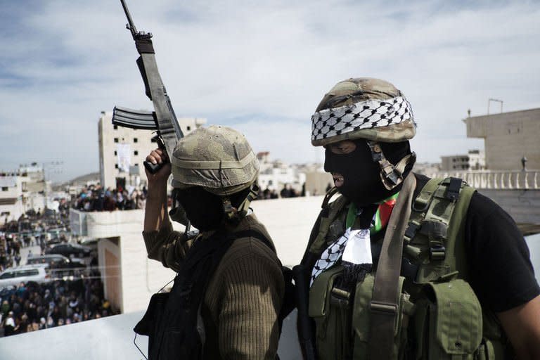 Palestinian militants of the Al-Aqsa Martyrs Brigades stand guard on the roof of a building in the West Bank village of Saair on February 25, 2013. Gaza militants from Fatah's Al-Aqsa Martyrs Brigades have fired a rocket at Israel in a "preliminary" step after one of its men died following an Israeli interrogation