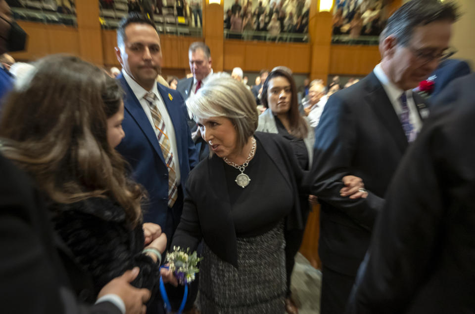 New Mexico Gov. Michelle Lujan Grisham, center, accompanied by her husband Manuel Cordova, right, arrives to deliver her State of the State address at the opening day of an annual legislative session in the House of Representatives in Santa Fe, N.M., on Tuesday, Jan. 17, 2023. Lujan Grisham called for new gun control laws and greater accountability for firearms manufacturers while denouncing recent drive-by shootings against state legislators and a national "scourge" of violence. (AP Photo/Andres Leighton)