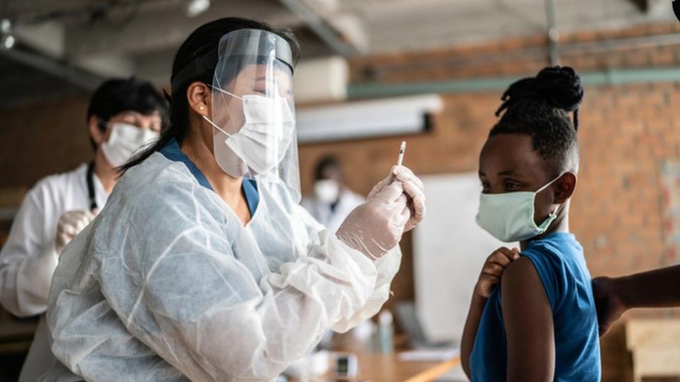 Una profesional sanitaria vacuna a un menor.