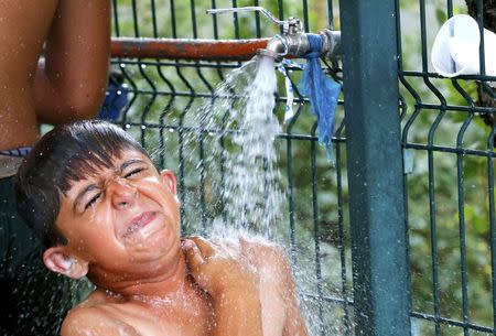 A child of Afghan migrants washes himself in an improvised shelter outside a brick factory in Subotica, Serbia July 27, 2015. REUTERS/Laszlo Balogh