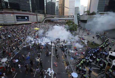 Riot police fire teargas to disperse protesters, during clashes after thousands of protesters blocked the main street to the financial Central district (background) outside the government headquarters in Hong Kong September 28, 2014. REUTERS/Stringer