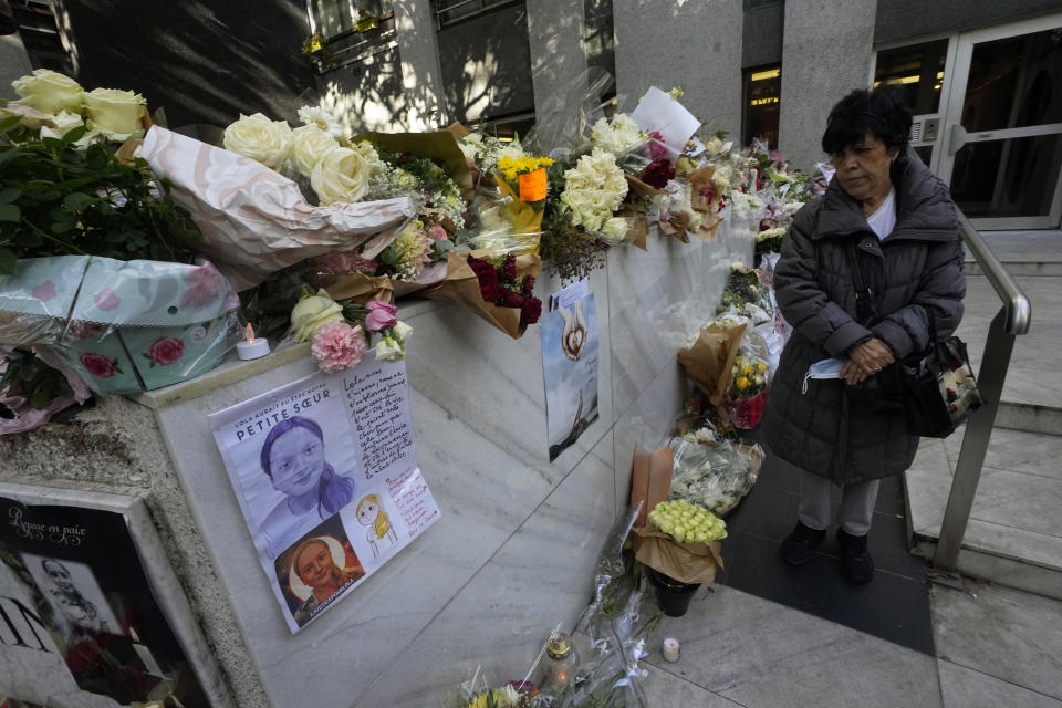 A woman stands outside the building where the body of 12-year-old schoolgirl was discovered in a trunk, in Paris, Wednesday, Oct. 19, 2022. France has been "profoundly shaken" by the murder of a 12-year-old schoolgirl, whose body was found in a plastic box, dumped in a courtyard of a building in northeastern Paris, the government spokesman Olivier Veran said on Wednesday. (AP Photo/Michel Euler)