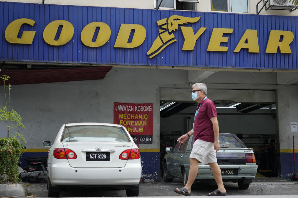 A man wearing a face mask walks in front of a Goodyear shop in Bukit Jalil, outskirts of Kuala Lumpur, Malaysia, Friday, June 11, 2021. A Malaysian court on Thursday ruled in favor of 65 migrant workers who sued U.S. tiremaker Goodyear for underpaying them, their lawyer said, calling it a victory for foreign employees. (AP Photo/Vincent Thian)