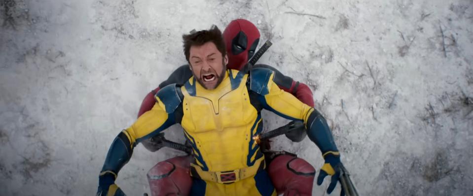 Deadpool holds Wolverine from behind as they both sit in the snow