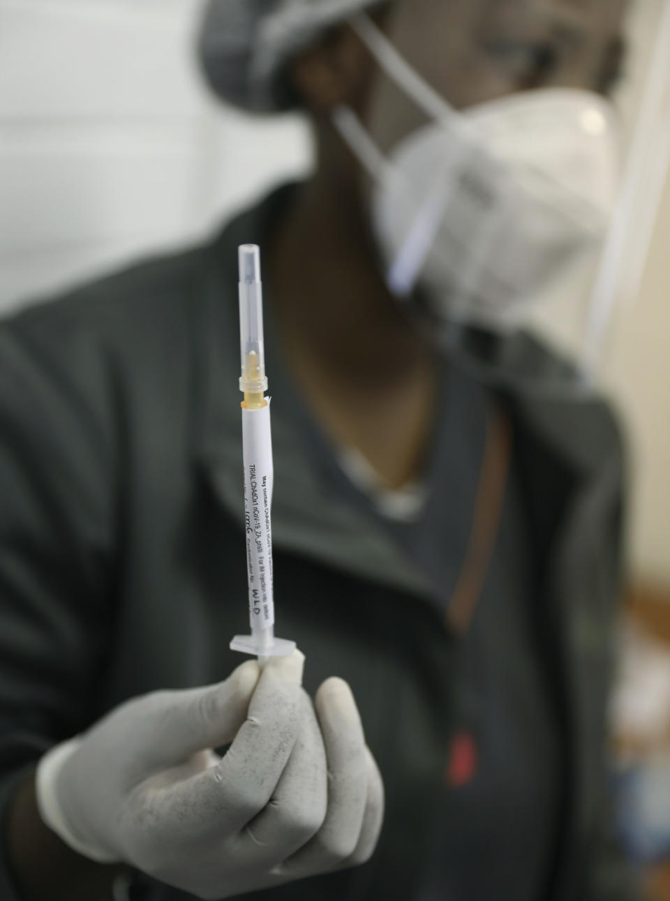 FILE - In this Wednesday, June 24, 2020 file photo, a medical staff member prepares a syringe, at the Chris Hani Baragwanath hospital in Soweto, Johannesburg. Refrigeration, cargo planes, and, above all, money: All risk being in short supply for the international initiative to get coronavirus vaccines to the world’s most vulnerable people. (AP Photo/Siphiwe Sibeko, File)