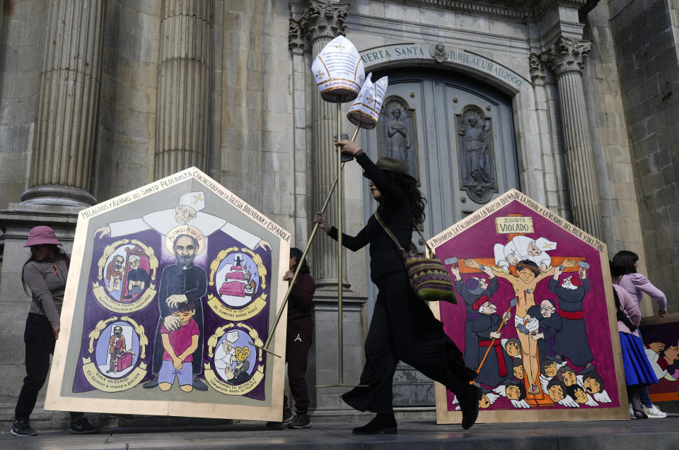 Una mujer ayuda a montar la escena para una protesta organizada por el grupo feminista Mujeres Creando, en reclamo de condenas para los sacerdotes acusados de pederastia, en las afueras de la Catedral Metropolitana en La Paz, Bolivia, el jueves 16 de mayo de 2024. (AP Foto/Juan Karita)