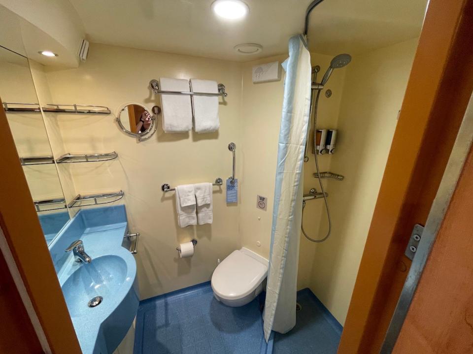 An image shows the cruise cabin's bathroom, sink, and shower.