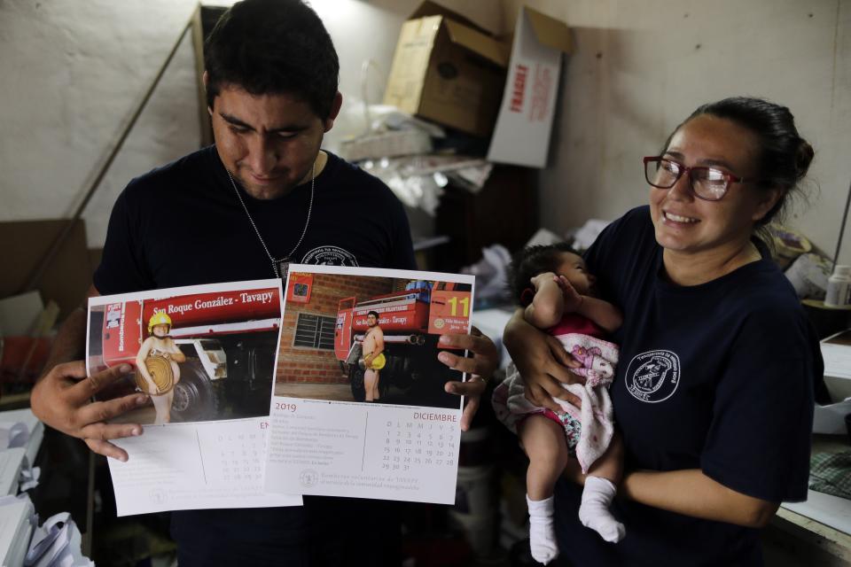 In this Jan. 12, 2019 photo, firefighter Fatima Olmedo, right, holds her two-month-old baby Samara as her husband Rodrigo Gimenez holds calendar pages with their photos posing nude, in Asuncion, Paraguay. Members of the volunteer firefighter unit in Paraguay have stripped naked in a calendar to raise money and demand resources from the government for their station in a small city on the outskirts of the capital.(AP Photo/Jorge Saenz)