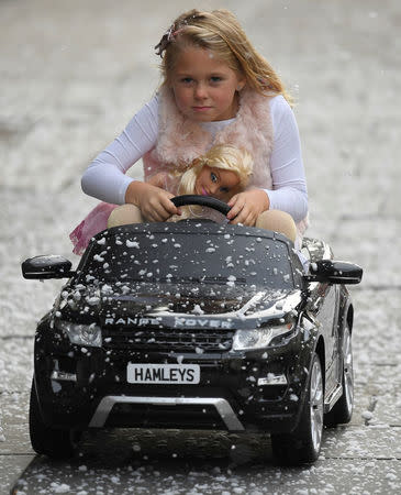 Six year old Lillie reacts as she poses with a children's Range Rover Evoque ride-on car and a Barbie fashion doll, which form part of the selection of predicted top sellers this Christmas at the Hamleys toy store in London, Britain, October 12, 2017. REUTERS/Toby Melville