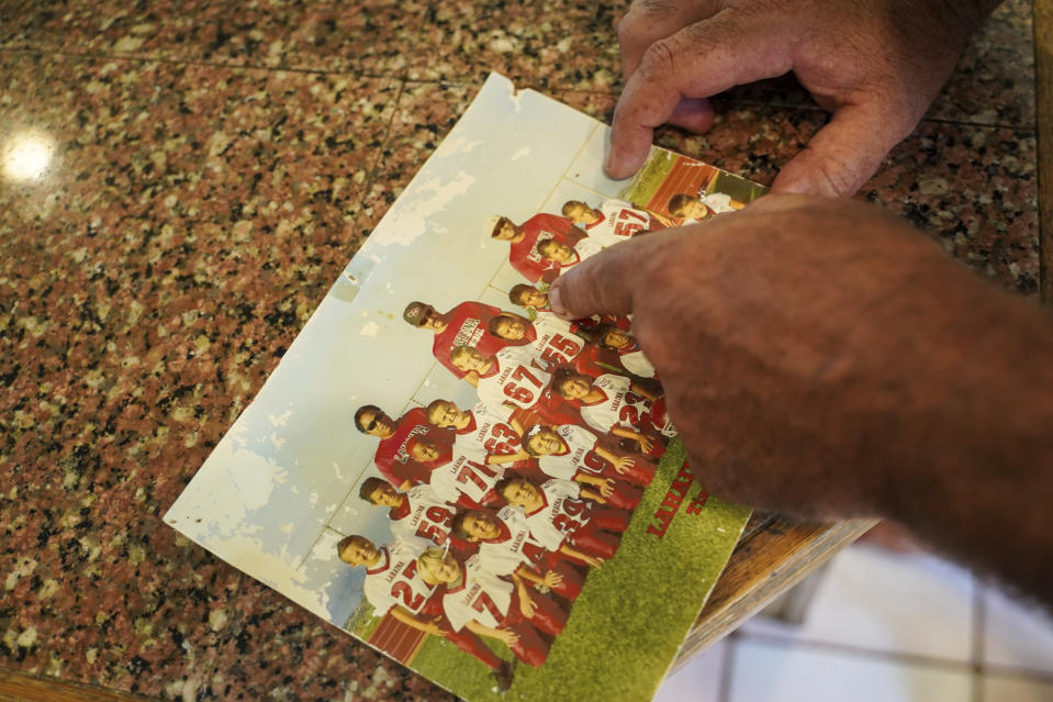 The father of Lahainaluna High School tight end and linebacker Tevainui Loft, Wyatt, points at a photo of Tevainui and teammates of the Lahainaluna Chiefs of 2013 at their home Saturday, Oct. 21, 2023, in Lahaina, Hawaii. Lahainaluna’s varsity and junior varsity football teams are getting back to normal since the devastating wildfire in August. (AP Photo/Mengshin Lin)