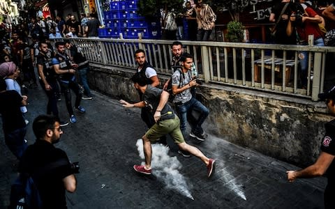 An LGBTI rights activist runs as people march on Sunday in Istanbul - Credit: AFP