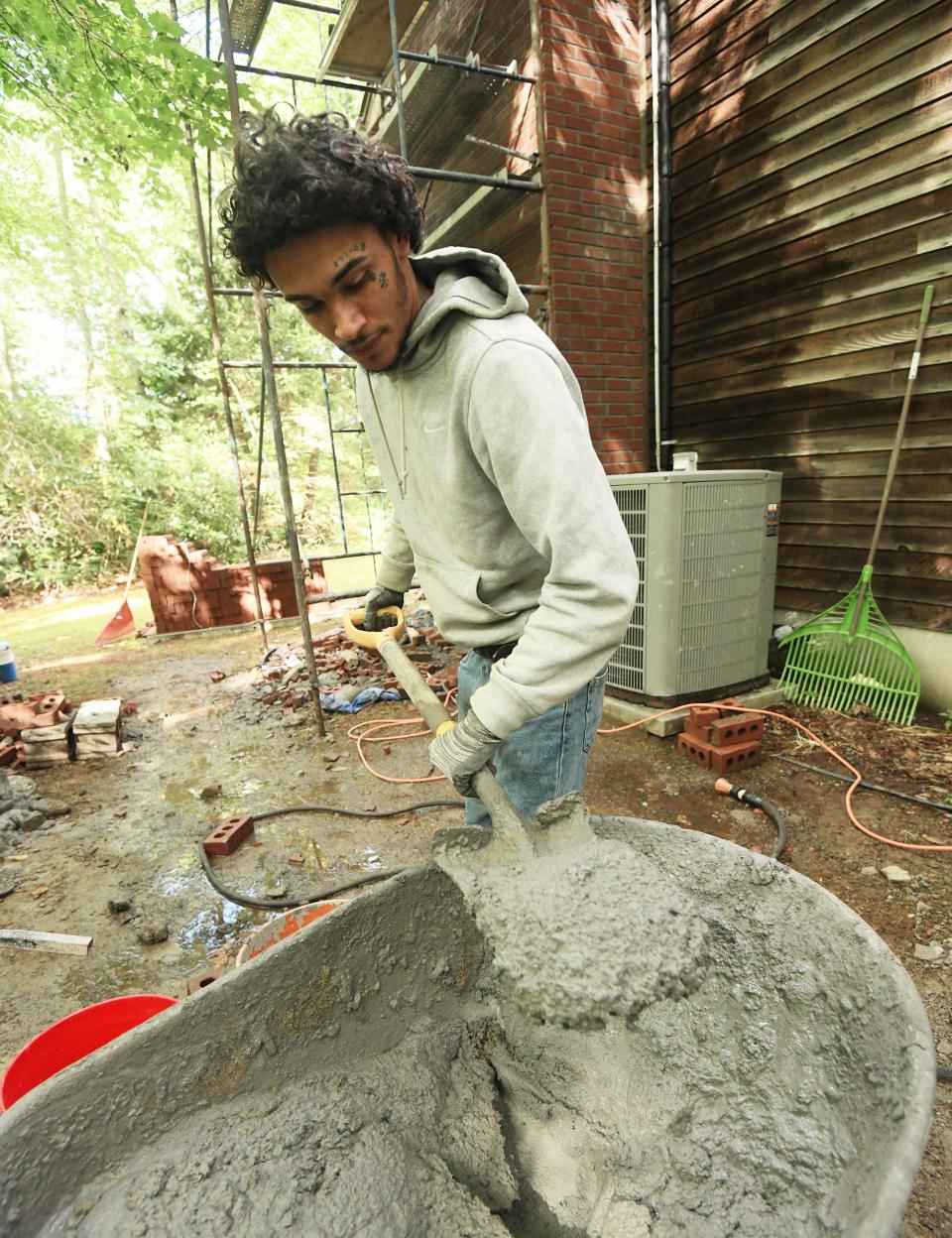Malcom Greene, 22, of Norwich, mixes a bucket of mortar to bring to Jesse Baier of Colchester, co-owner of JLS Premier Masonry & Construction in Colchester, as they work on replacing a chimney in Colchester Sept. 8.