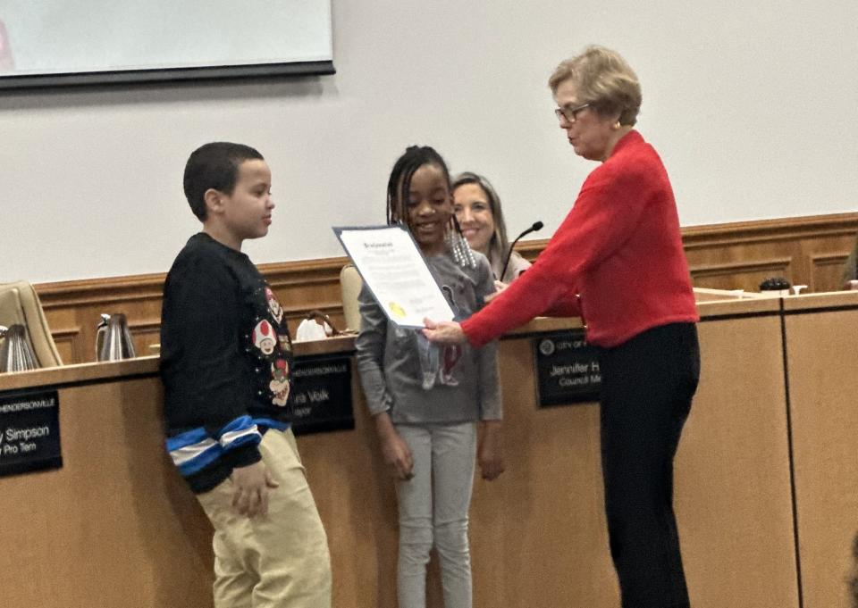 Hendersonville Mayor Barbara Volk presents the Black History Month Proclamation by the city to two students, JT Williams, left, and Ibrahim Newborn.