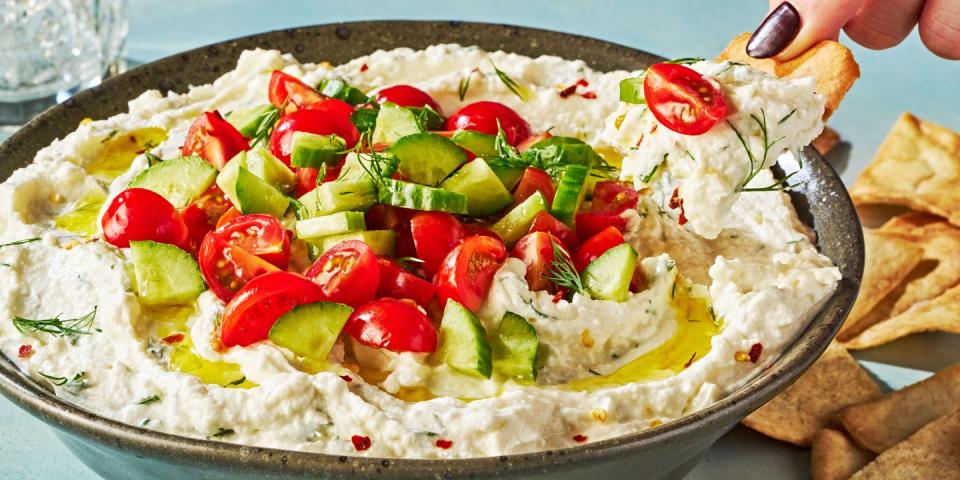 feta dip in a bowl topped with tomatoes and cucumber