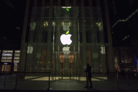 An employee stands in front of the Apple flagship store on 5th Avenue in New York April 22, 2015. REUTERS/Brendan McDermid