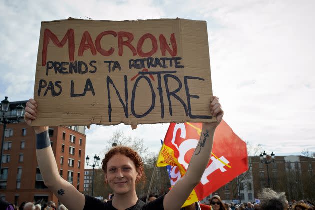 A protester holds a placard reading 'Macron take your pension, not ours'