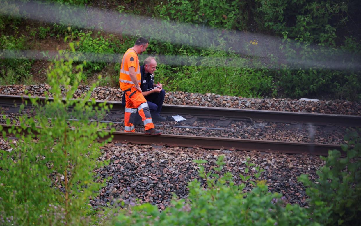 A SNCF railway worker and a police officer work at the site where saboteurs targeted France's high-speed train network