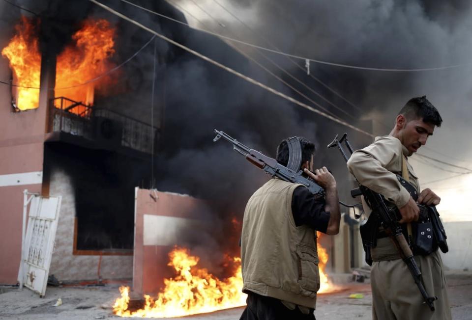 Bewaffnete Kurden stehen während heftiger Zusammenstöße mit gezückten Maschinengewehren vor dem brennenden Haus eines schiitischen Militärs in Tuz Khurmato im Irak. (Bild: Goran Tomasevic/REUTERS)