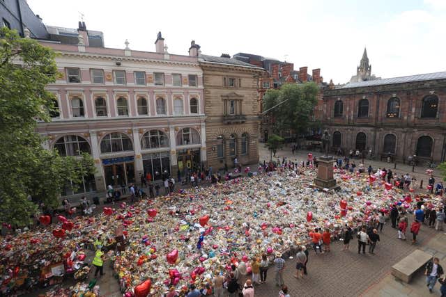 People look at flowers and tributes left in St Ann’s Square in Manchester following the terror attack 