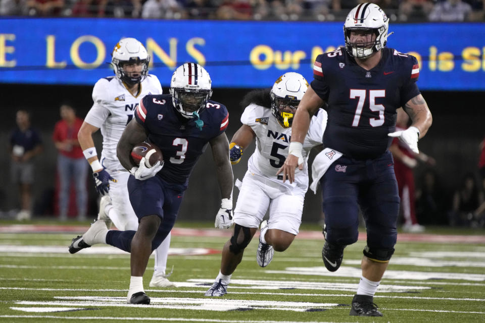 Arizona running back Jonah Coleman (3) runs behind offensive lineman Josh Baker during the first half the team's NCAA college football game against Northern Arizona, Saturday, Sept. 2, 2023, in Tucson, Ariz. (AP Photo/Rick Scuteri)