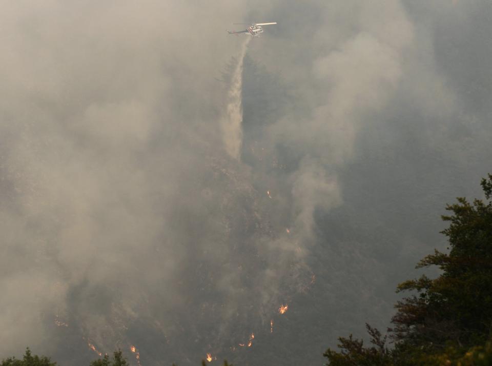 A helicopter drops ocean water on a wildfire burning on Pfeiffer Ridge in Big Sur